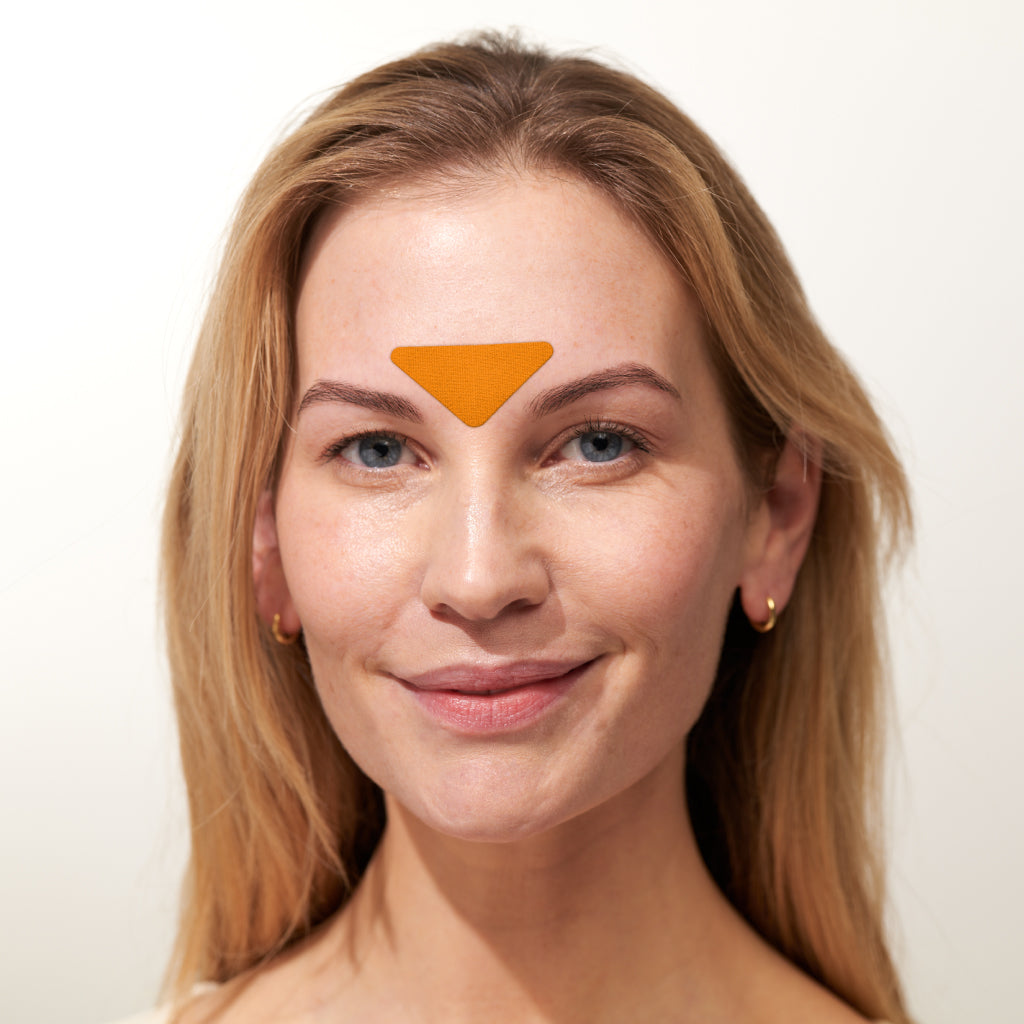 Model trägt APRICOT Zornesfalten Patches mit Niacinamid aus Bio-Baumwolle für die Stirnpartie